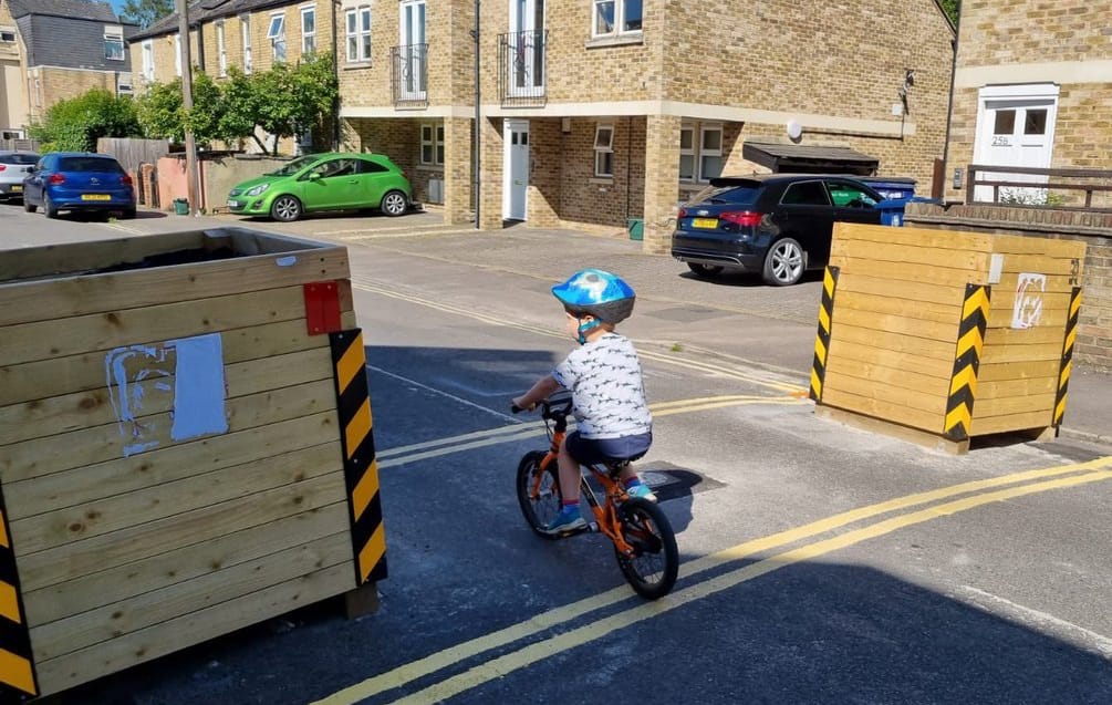 A small child on a bicycle rides through a traffic filter.