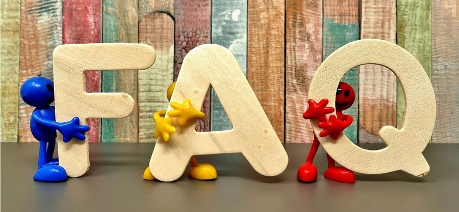 Little clay figures hold three wooden letters spelling FAQ.